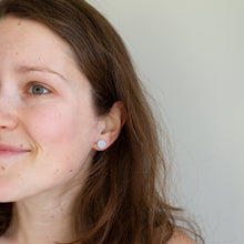 Load image into Gallery viewer, Model wears tiny pale blue textured shell design polymer clay studs.