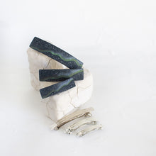 Load image into Gallery viewer, Three dark blue polymer clay barrettes with a northern lights design are arranged on a white rock against a white background.
